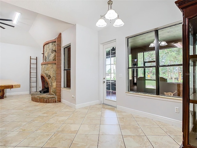 tiled entrance foyer featuring ceiling fan with notable chandelier, a fireplace, and lofted ceiling