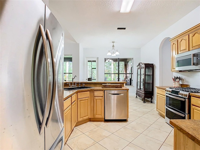 kitchen featuring appliances with stainless steel finishes, an inviting chandelier, sink, and a wealth of natural light