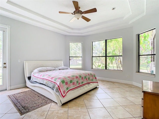 tiled bedroom featuring ceiling fan and a raised ceiling