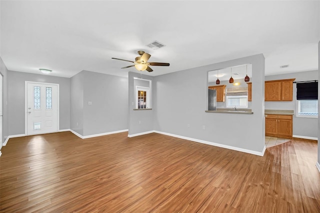 unfurnished living room featuring wood-type flooring, sink, and ceiling fan