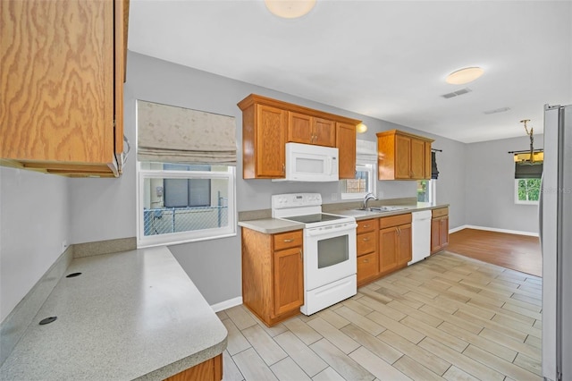 kitchen with light wood-type flooring, white appliances, and sink