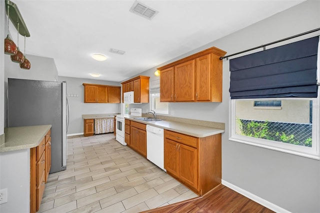 kitchen with light hardwood / wood-style flooring, white appliances, plenty of natural light, and sink