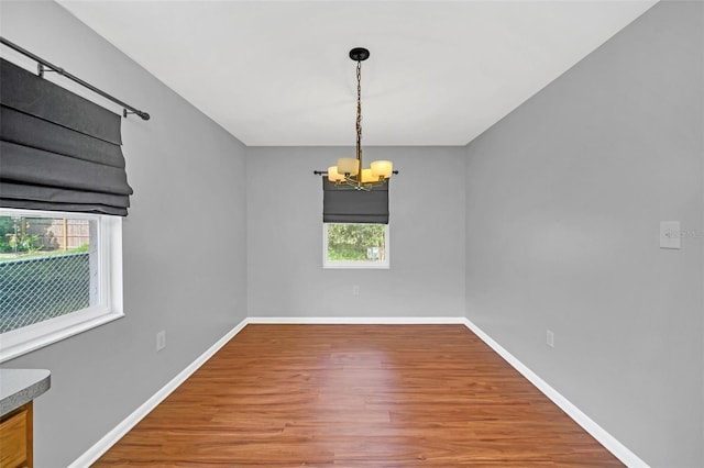 empty room with an inviting chandelier and hardwood / wood-style floors