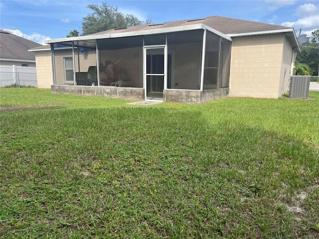 back of house with a sunroom, cooling unit, and a lawn