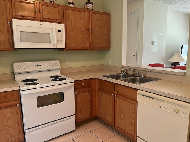 kitchen with a textured ceiling, white appliances, light tile patterned flooring, and sink