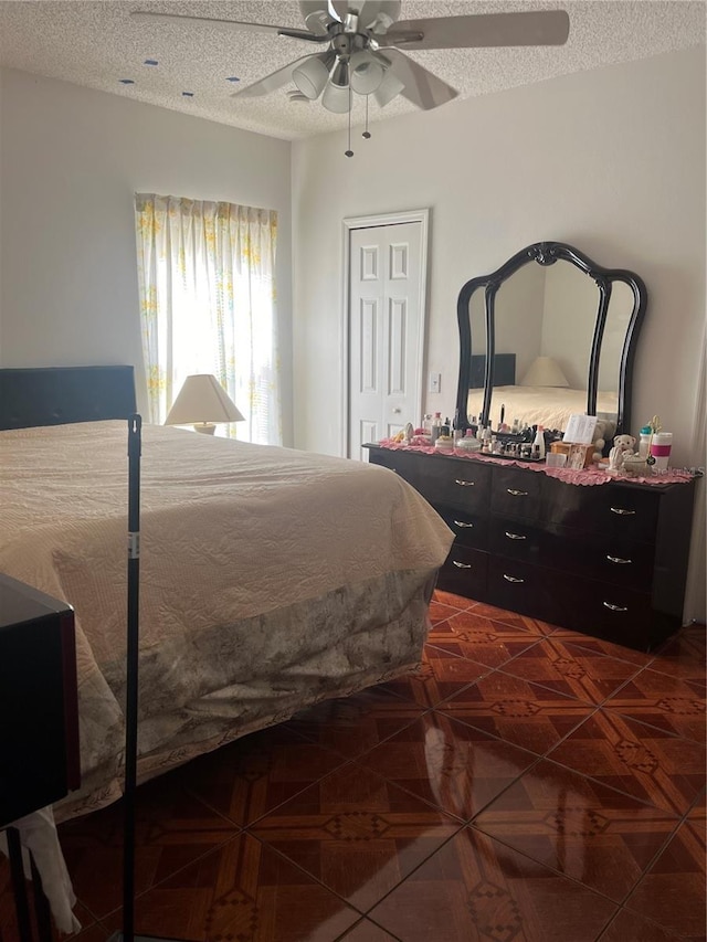 bedroom with ceiling fan, a textured ceiling, a closet, and dark parquet floors