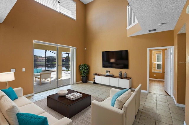 living room with a textured ceiling, a towering ceiling, and light tile patterned floors