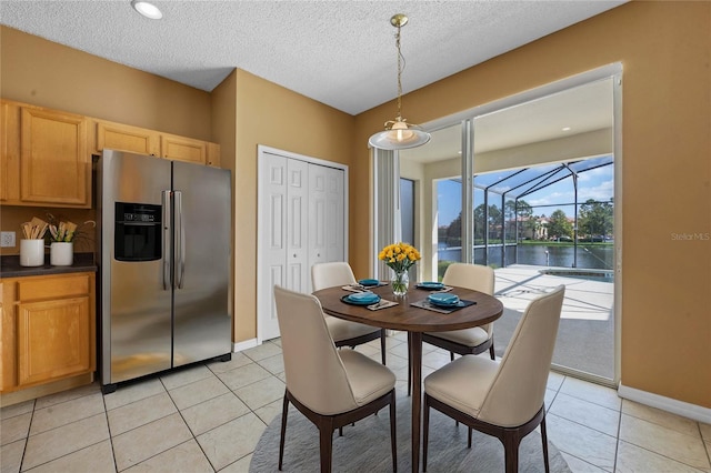 tiled dining area with a textured ceiling and a water view