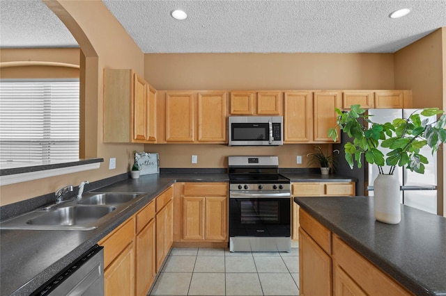 kitchen with light tile patterned floors, a textured ceiling, appliances with stainless steel finishes, and sink