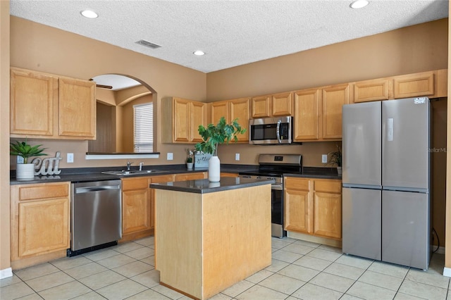 kitchen featuring appliances with stainless steel finishes, light tile patterned flooring, a kitchen island, and sink