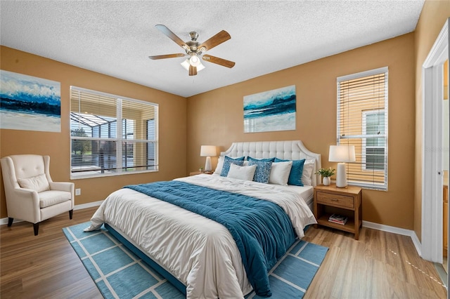 bedroom with light hardwood / wood-style flooring, multiple windows, ceiling fan, and a textured ceiling