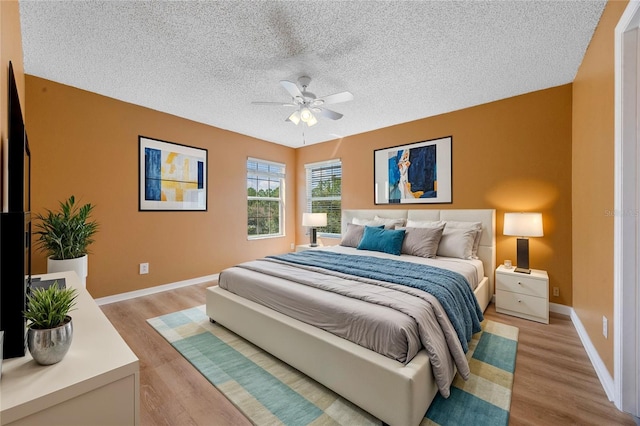 bedroom featuring light wood-type flooring, ceiling fan, and a textured ceiling