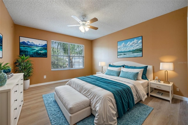 bedroom with light wood-type flooring, a textured ceiling, and ceiling fan