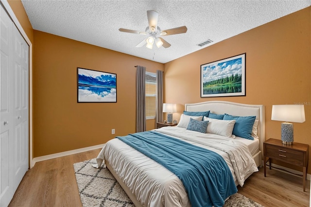 bedroom with ceiling fan, a textured ceiling, a closet, and light hardwood / wood-style flooring