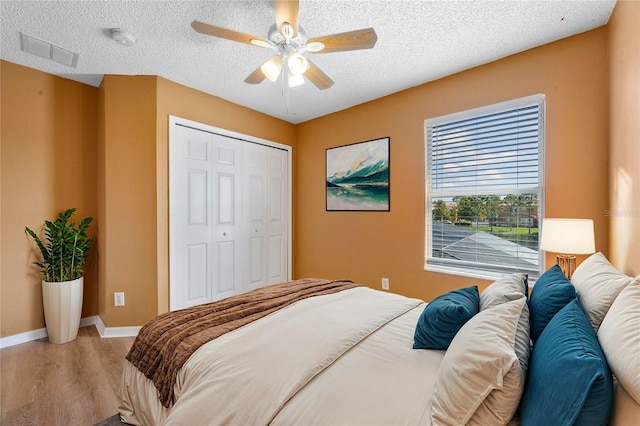 bedroom featuring a textured ceiling, wood-type flooring, ceiling fan, and a closet