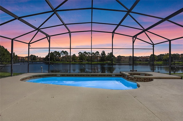 pool at dusk with glass enclosure, a water view, and a patio