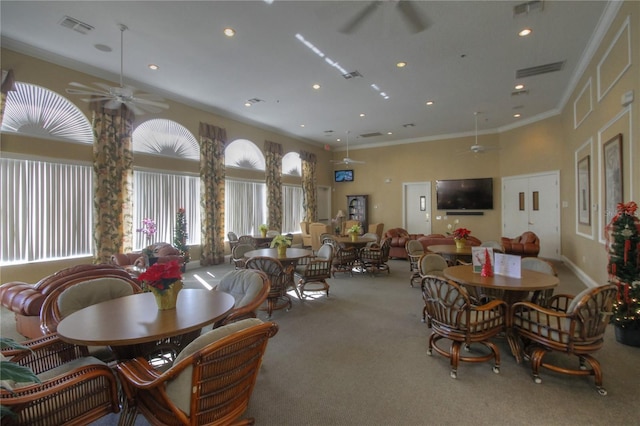 carpeted dining area featuring crown molding, a high ceiling, and ceiling fan