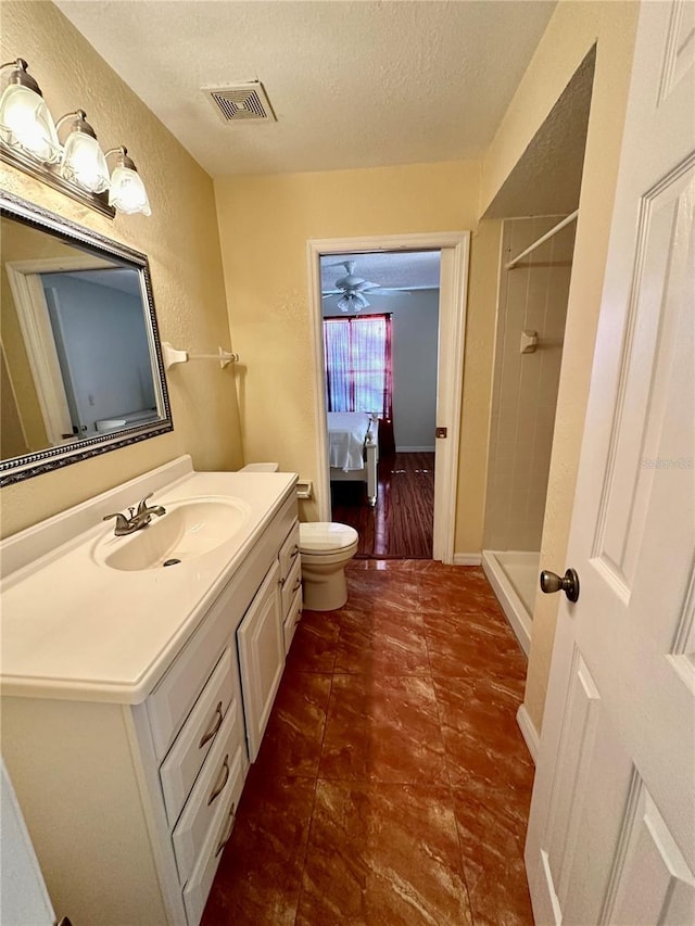 bathroom featuring vanity, a shower, a textured ceiling, and toilet