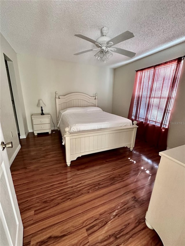 bedroom with ceiling fan, a textured ceiling, and dark hardwood / wood-style flooring