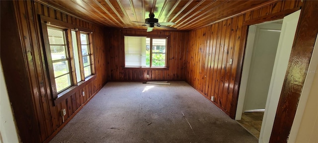 unfurnished room featuring wooden walls, ceiling fan, carpet, and wooden ceiling