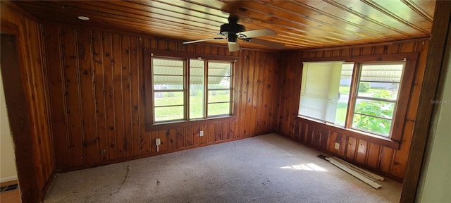 empty room featuring a baseboard radiator, ceiling fan, light carpet, wooden ceiling, and wooden walls