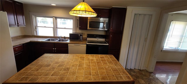 kitchen with tile countertops, black stove, dishwasher, pendant lighting, and sink