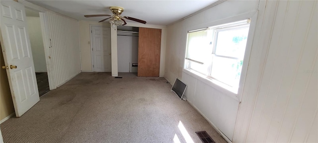 unfurnished bedroom featuring crown molding, light colored carpet, a closet, and ceiling fan