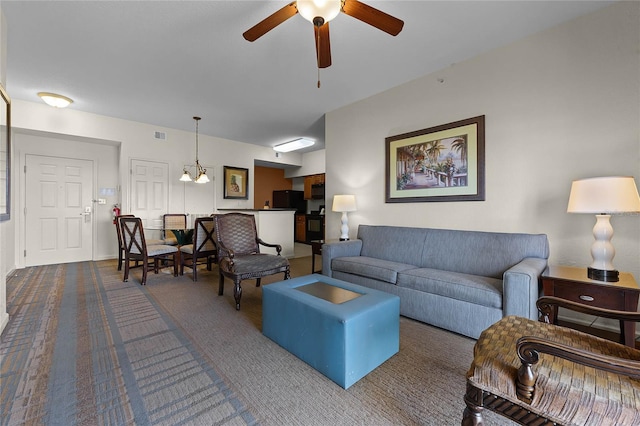 living room featuring ceiling fan with notable chandelier and carpet