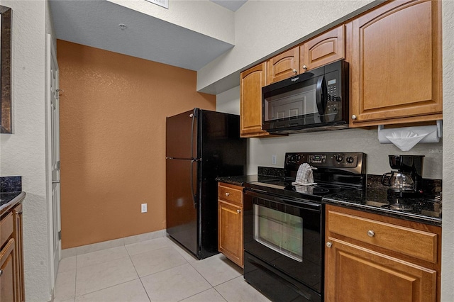 kitchen featuring dark stone counters, light tile patterned floors, and black appliances