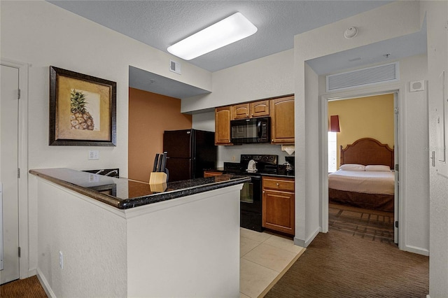 kitchen with a textured ceiling, black appliances, kitchen peninsula, and light carpet