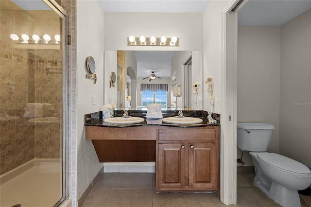 bathroom with vanity, a shower with shower door, toilet, and tile patterned floors