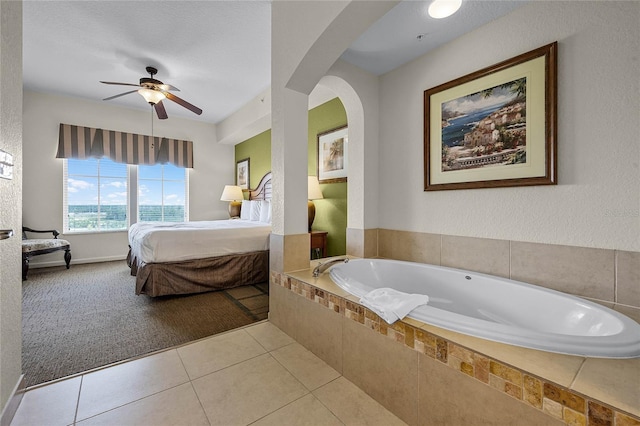 bathroom with tiled tub, a textured ceiling, tile patterned floors, and ceiling fan