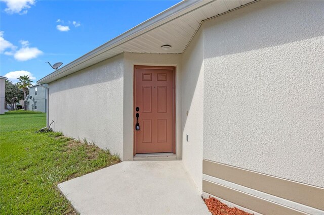 doorway to property featuring a lawn