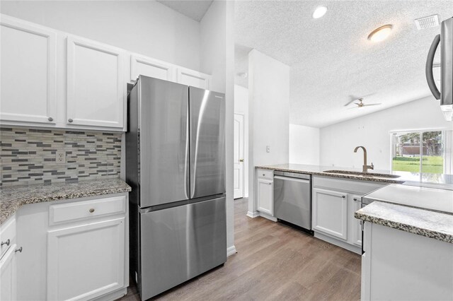 kitchen with white cabinets, sink, tasteful backsplash, light hardwood / wood-style flooring, and appliances with stainless steel finishes