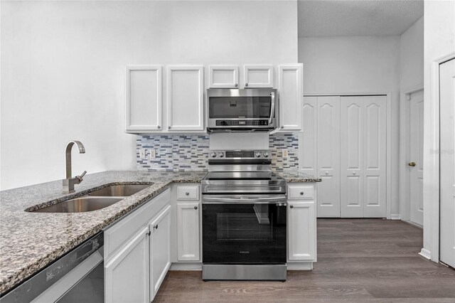 kitchen with light stone countertops, dark wood-type flooring, stainless steel appliances, and white cabinets