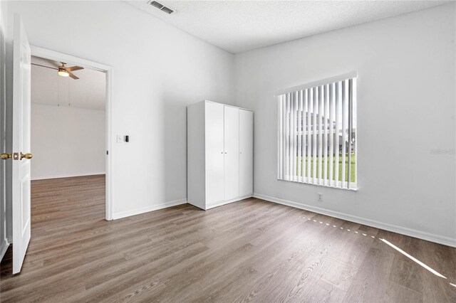 empty room featuring light hardwood / wood-style flooring, ceiling fan, and a textured ceiling