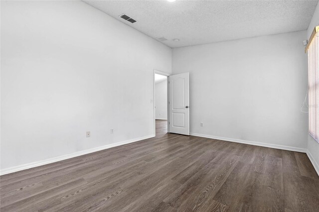 empty room featuring a textured ceiling and dark hardwood / wood-style flooring