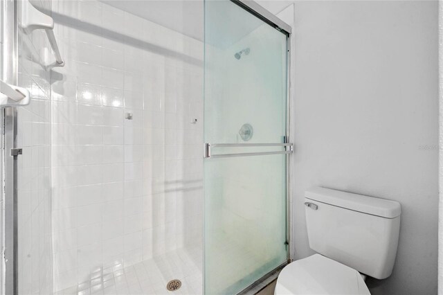 bathroom with a shower with shower door and toilet