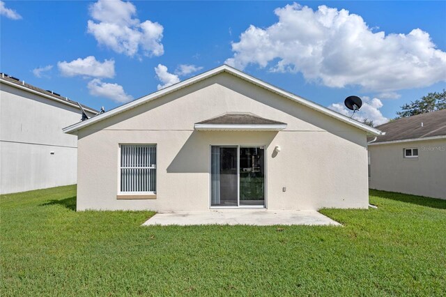 back of property with a yard and a patio