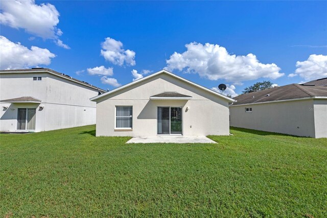 rear view of property featuring a lawn and a patio area