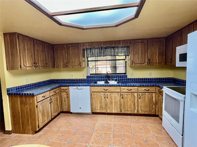 kitchen with sink, white appliances, light tile patterned floors, and a skylight