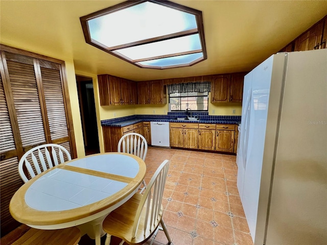 kitchen with sink, white appliances, and light tile patterned flooring