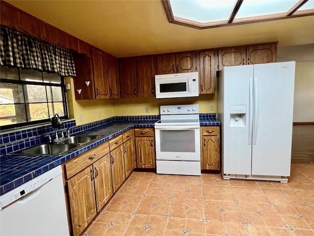 kitchen with sink, light tile patterned flooring, white appliances, and tile countertops