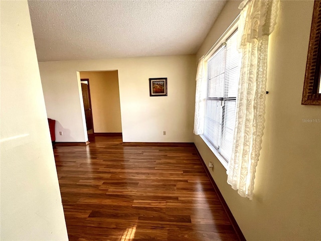 empty room featuring a textured ceiling and dark hardwood / wood-style flooring