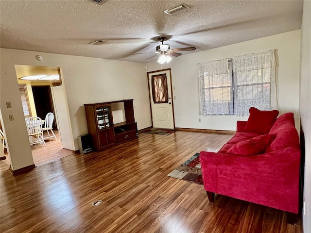 living room featuring ceiling fan, a textured ceiling, and wood-type flooring