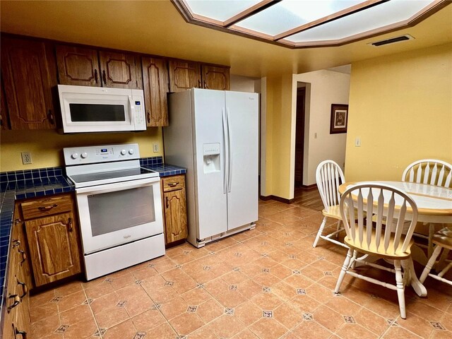 kitchen with white appliances, light tile patterned floors, and tile countertops