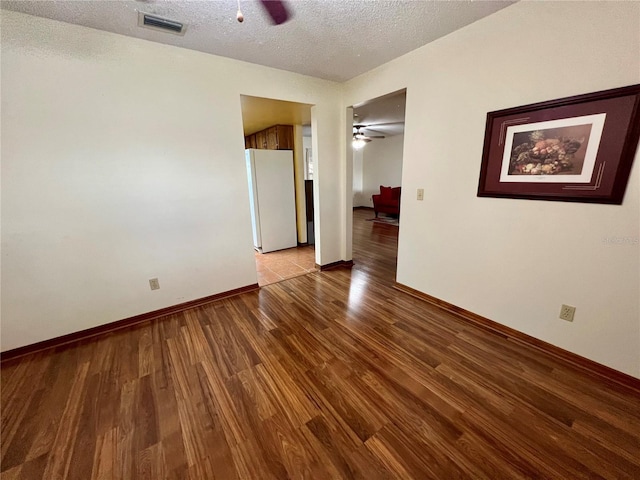 empty room with ceiling fan, light hardwood / wood-style floors, and a textured ceiling