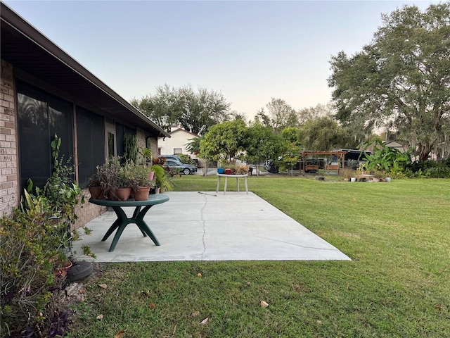 patio terrace at dusk featuring a yard