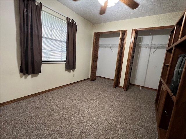 unfurnished bedroom with multiple closets, a textured ceiling, ceiling fan, and carpet floors