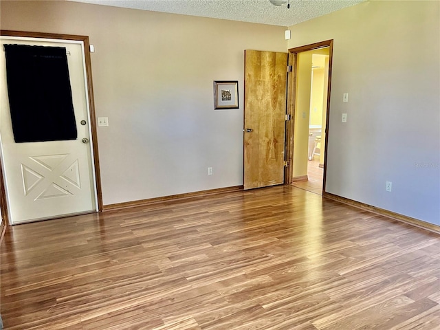 unfurnished room featuring a textured ceiling and light hardwood / wood-style flooring